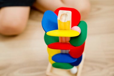 Tahta mermer yarış kulesi. Çocuklar oyun oynamak için oyun oynarlar. Çocuk topu başlangıç pozisyonuna getiriyor. Evdeki etkinlikler. Tablo ve zemin oyunu.