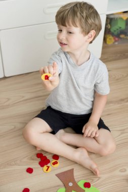 Elma ağacını numaralarla hissettim. Çocukların saymayı öğrenmesi için anaokulu uygulaması. Montessori konsepti, erken eğitim. Çocuk yerde oturuyor ve oynuyor. 