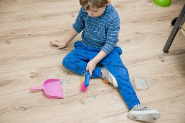 Görev binası. Küçük çocuk yerleri süpürüyor. Evde günlük işler, ev işleri..