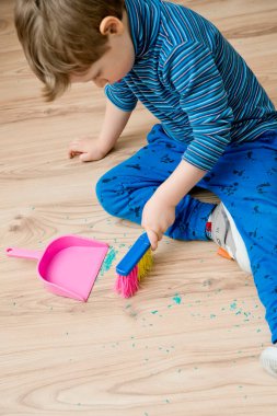 Görev binası. Küçük çocuk yerleri süpürüyor. Evde günlük işler, ev işleri..