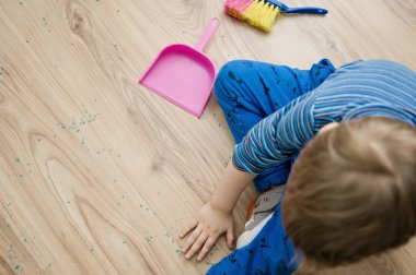 Görev binası. Küçük çocuk yerleri süpürüyor. Evde günlük işler, ev işleri..