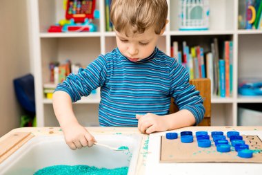 Evde okul var. DIY hesap makinesi. Saymayı öğrenmek. Plastik şişe kapağı ve renkli pirinç. Anaokulu çocukları için Montessori aleti. Oyun yoluyla öğrenme.