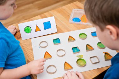 Çocuk geometrik şekilleri öğreniyor. Güzel motor beceriler. Anaokulu ya da özel görevler. Çocukların erken eğitimi. Montessori yöntembilimi.