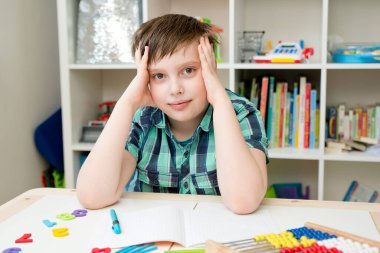 Okula geri dön. Okul malzemeleriyle masada oturan mutlu çocuk. Matematik dersi. Masada renkli sayılar var. Evde öğreniyorum. Tekrar karantinaya alın. Tecrit.