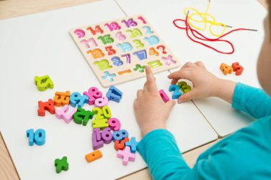 Çocuk oyun yoluyla numaraları öğreniyor. Tahta sayılar ve ayakkabı bağcıklarıyla duyusal aktivite. Evde eğitim, okul öncesi eğitim, Montessori metodolojisi. sayılar dizisi, aritmetik problemler.