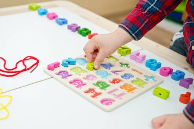 Çocuk oyun yoluyla numaraları öğreniyor. Tahta sayılar ve ayakkabı bağcıklarıyla duyusal aktivite. Evde eğitim, okul öncesi eğitim, Montessori metodolojisi. sayılar dizisi, aritmetik problemler.