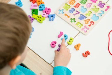 Çocuk oyun yoluyla numaraları öğreniyor. Tahta sayılar ve ayakkabı bağcıklarıyla duyusal aktivite. Evde eğitim, okul öncesi eğitim, Montessori metodolojisi. sayılar dizisi, aritmetik problemler.