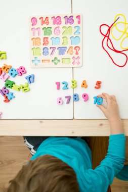 Çocuk oyun yoluyla numaraları öğreniyor. Tahta sayılar ve ayakkabı bağcıklarıyla duyusal aktivite. Evde eğitim, okul öncesi eğitim, Montessori metodolojisi. sayılar dizisi, aritmetik problemler.