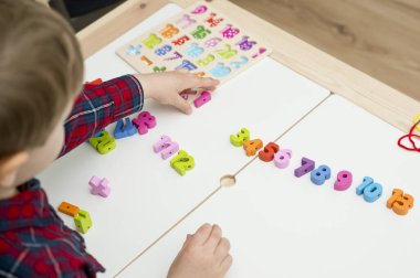Çocuk oyun yoluyla numaraları öğreniyor. Tahta sayılar ve ayakkabı bağcıklarıyla duyusal aktivite. Evde eğitim, okul öncesi eğitim, Montessori metodolojisi. sayılar dizisi, aritmetik problemler.