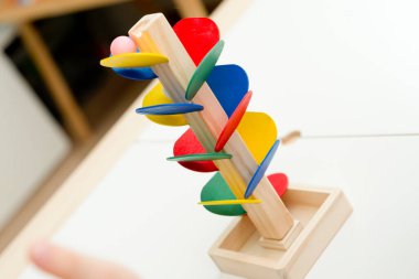 Tahta mermer yarış kulesi. Çocuklar oyun oynamak için oyun oynarlar. Çocuk topu başlangıç pozisyonuna getiriyor. Evdeki etkinlikler. Tablo ve zemin oyunu.