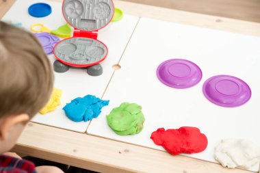 Oyun hamuruyla yemek yapmak. Çocuk farklı renkte plastiklerle ve plastik mutfak malzemeleriyle oynuyor..