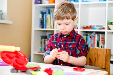 Oyun hamuruyla yemek yapmak. Çocuk farklı renkte plastiklerle ve plastik mutfak malzemeleriyle oynuyor..