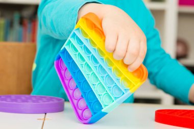 Çocuk duyusal oyuncak Pop-it ile oynuyor. Kaliteli motor becerileri için araç, saymaya başlamak için araç, birincil aritmetik işlemlerini öğrenmek. Parmak uyumu ve rahatlama için bir yatıştırıcı..