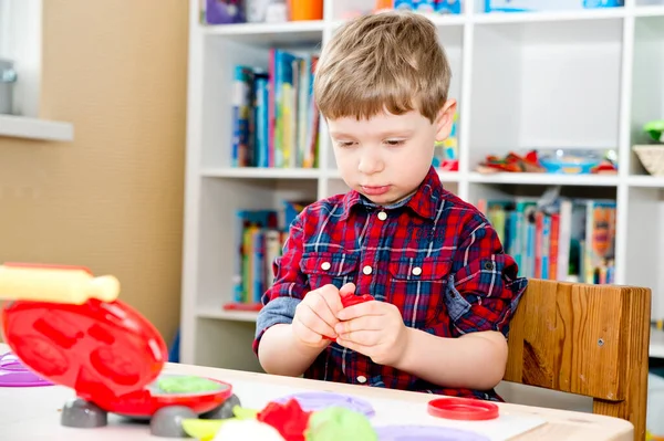 Oyun hamuruyla yemek yapmak. Çocuk farklı renkte plastiklerle ve plastik mutfak malzemeleriyle oynuyor..