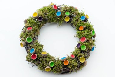 Beyaz bir masa üzerinde yosun ve süslemeli el yapımı Paskalya çelengi..