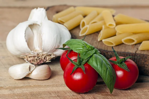 Pasta, tomate y ajo sobre fondo de madera — Foto de Stock