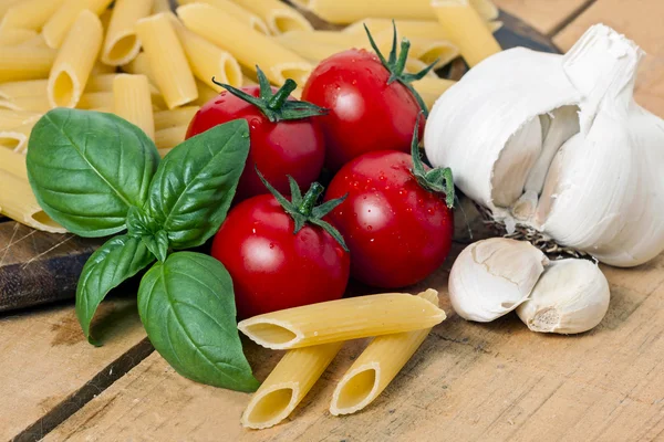 Pasta, tomate y ajo sobre fondo de madera — Foto de Stock
