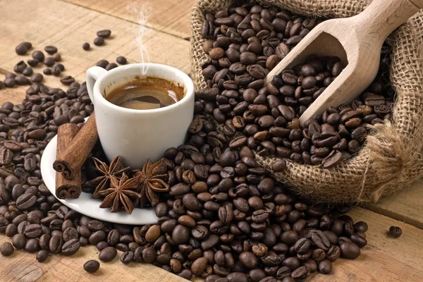 Filiżanka kawy i ziarna na drewnianym stole — Zdjęcie stockowe