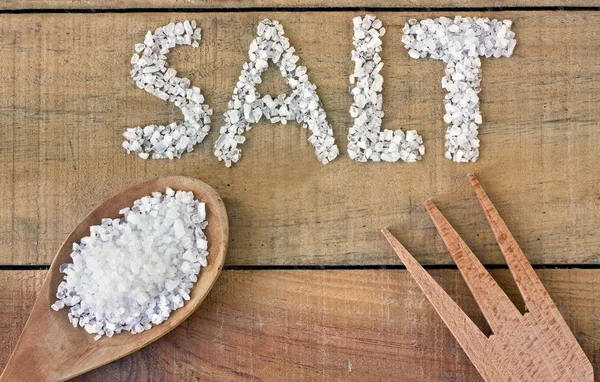 Salz im Löffel auf einem Holztisch — Stockfoto