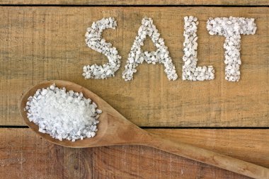 Salt in spoon on a wooden table clipart