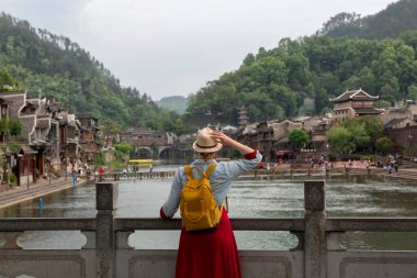 Feng Huang Antik Kasabası 'nın güzel manzarasına bakan genç bayan turist Hunan Eyaleti, Çin' deki ünlü turizm merkezi.