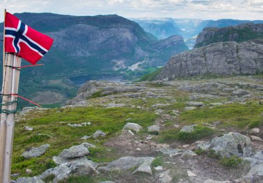 Göl kentini dramatik bir şekilde gören Norveç bayrağı ve arka planda fiyortlar. Güney Norveç 'teki fiyortların tepesinde - Avrupa Yürüyüşü ve Seyahat Konsepti