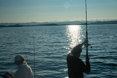 Stavanger Norveç yakınlarındaki bir teknede olta atan çift (jig fish fish)