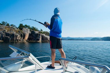 Stavanger Norveç yakınlarındaki bir teknede olta kamışlı erkek balıkçı.)