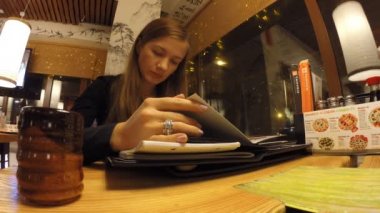 Kız menü Japon lokantasında okuyor