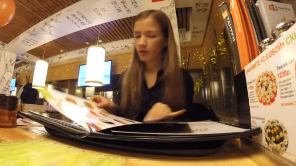 Het meisje is studeren in het Japanse restaurant menu — Stockvideo