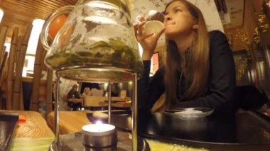 Kız bir Japon restoran Tanuki çay içecekler