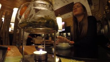 Kız bir Japon restoran Tanuki çay içecekler