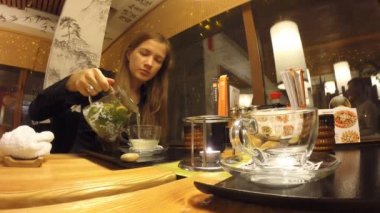 Kız bir Japon restoran Tanuki çay içecekler