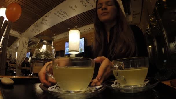 Das Mädchen trinkt Tee in einem japanischen Restaurant tanuki — Stockvideo