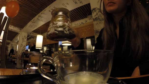 在日本的餐厅，狸猫的女孩喝茶 — 图库视频影像