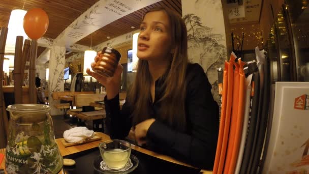 Flickan dricker te i en japansk restaurang Tanuki — Stockvideo