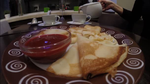 Meisje eet pannenkoeken met frambozenjam in een café-restaurant — Stockvideo