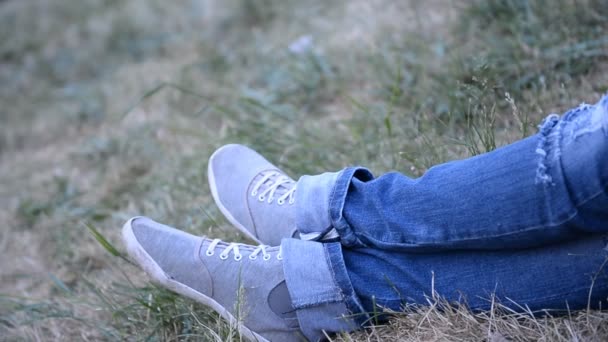 Odpoczynek w parku na świeżym powietrzu, nogi w jeans odzież — Wideo stockowe