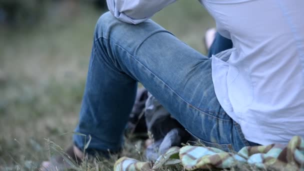 Pihenés a parkban, a szabadban, lábát farmer ruha — Stock videók