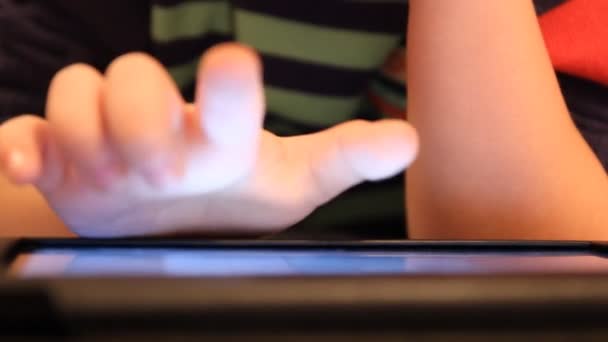 Ένα αγόρι παίζει το Tablet Pc. εγχώριες επιπλώσεις, τεχνητός φωτισμός — Αρχείο Βίντεο