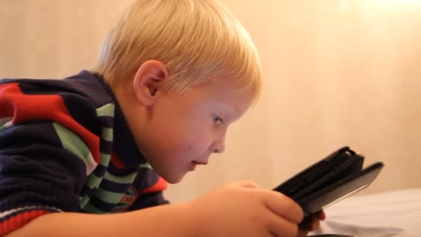 Un garçon joue dans la tablette. Ameublement, éclairage artificiel — Video