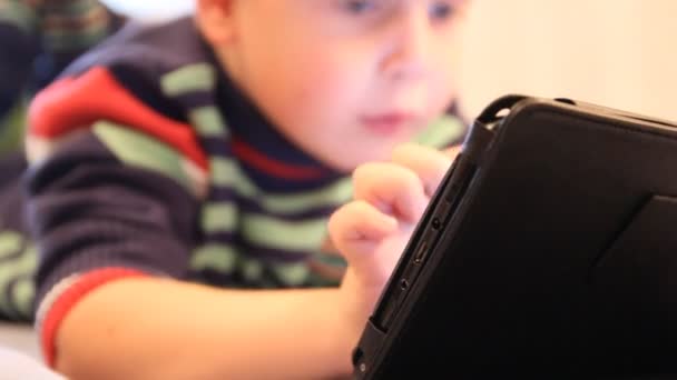 Хлопчик грає в планшетний ПК. будинок меблів, штучне освітлення — стокове відео
