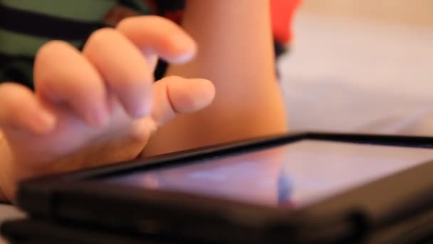 A boy plays in the Tablet PC. Home furnishings, artificial lighting — Stock Video