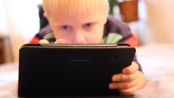 A boy plays in the Tablet PC. Home furnishings, artificial lighting — Stock Video