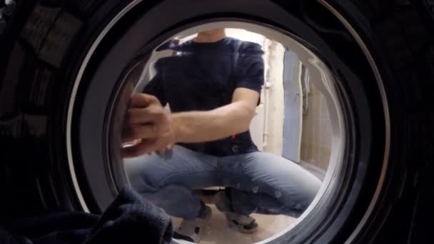 Внутри стиральная машина. Мужчина лежит на бельевой стирке — стоковое видео