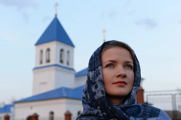 Девушка славянской внешности в шарфе на фоне церкви — стоковое фото