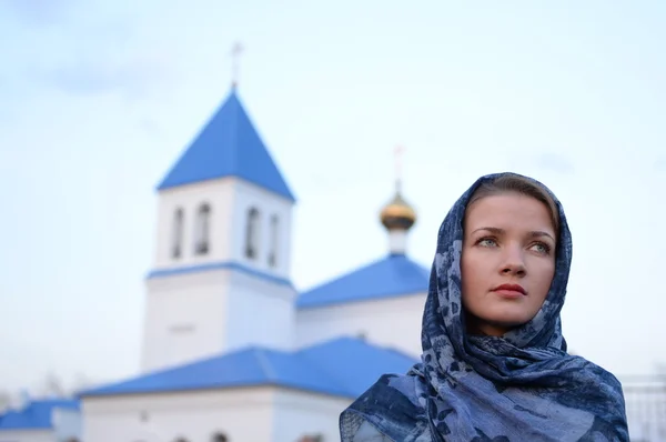 A girl of Slavic Russian appearance in a scarf on the background of the church Stock Picture