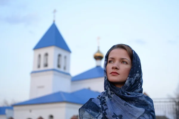 A girl of Slavic Russian appearance in a scarf on the background of the church Stock Photo