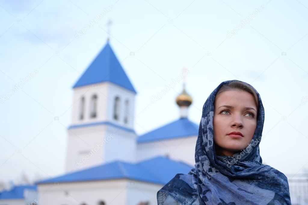 A girl of Slavic Russian appearance in a scarf on the background of the church