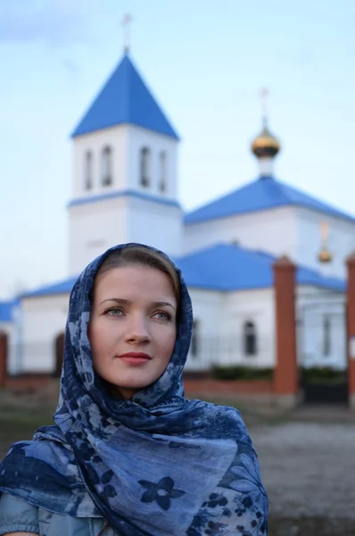 Una ragazza di aspetto russo slavo in una sciarpa sullo sfondo della chiesa — Foto Stock